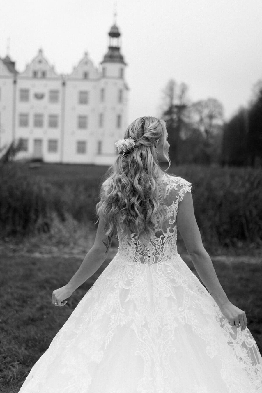 Braut steht im pompösen Brautkleid vor dem Schloss Ahrensburg