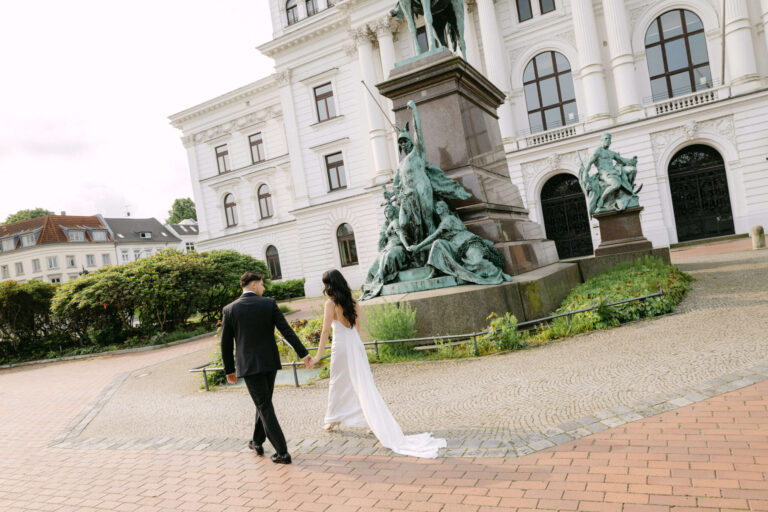 Das Brautpaar geht Hand in Hand über den Platz des Rathaus Hamburg aufgenommen durch die Hochzeitsfotografin Laura Kaiser