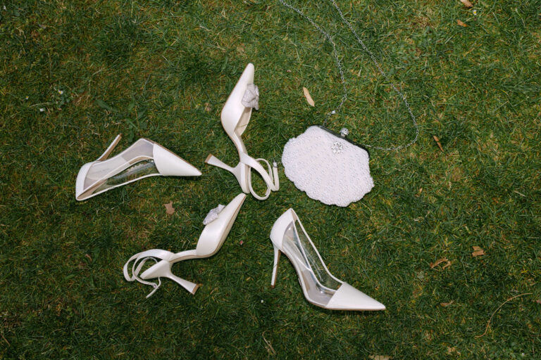 Brautschuhe und Brauttasche liegen auf einer Wiese.