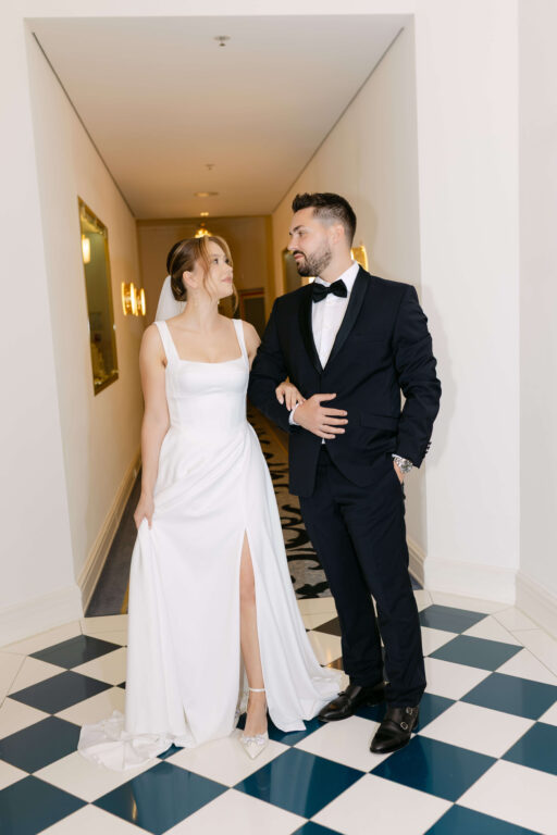 Das Brautpaar steht im Flur im Hotel Atlantic. in Hamburg. Er trägt einen klassischen schwarzen Anzug und die Braut trägt ein langes klassischesn Brautkleid mit Corsage.