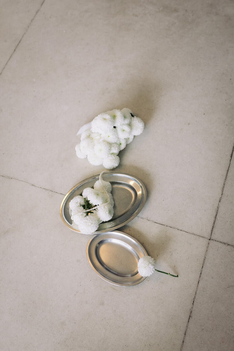 Die Blumen liegen auf zwei Silbertabletten auf dem Boden.