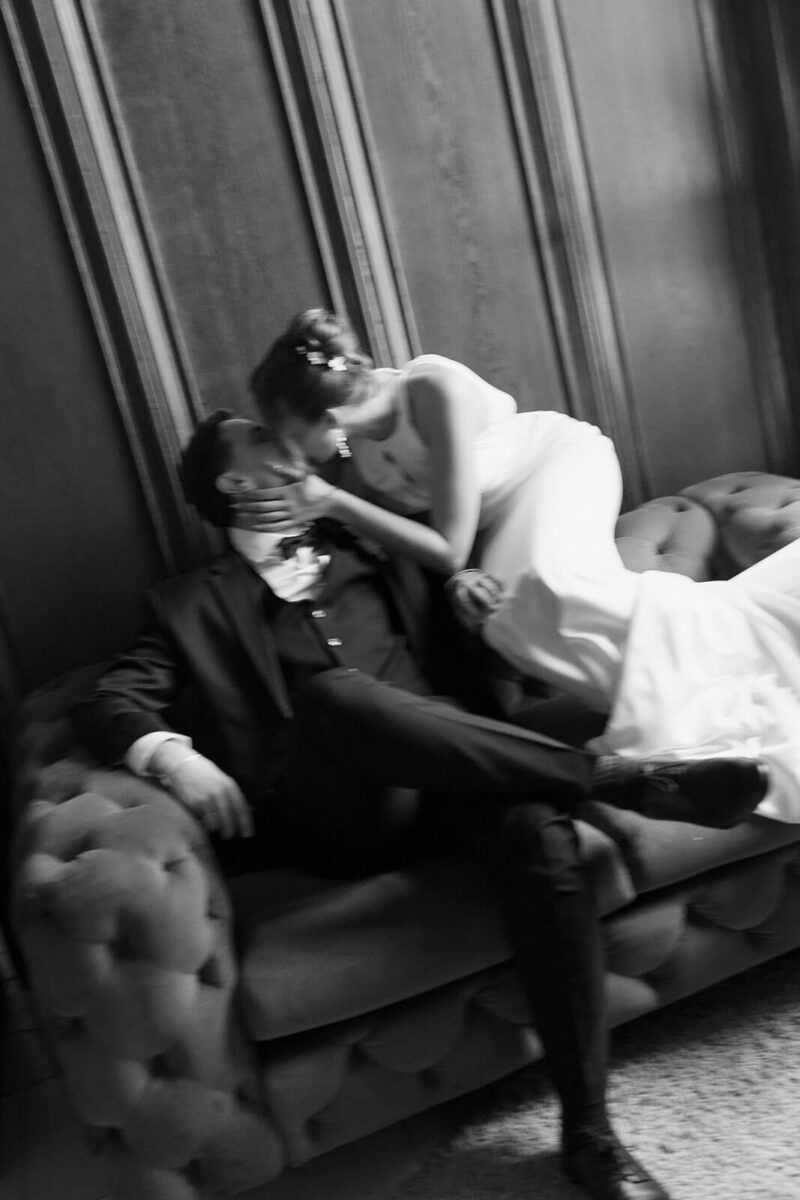 Die Braut beugt sich zum Bräutigam herunter und gibt einen Kuss. Das Bild ist leicht verschwommen.