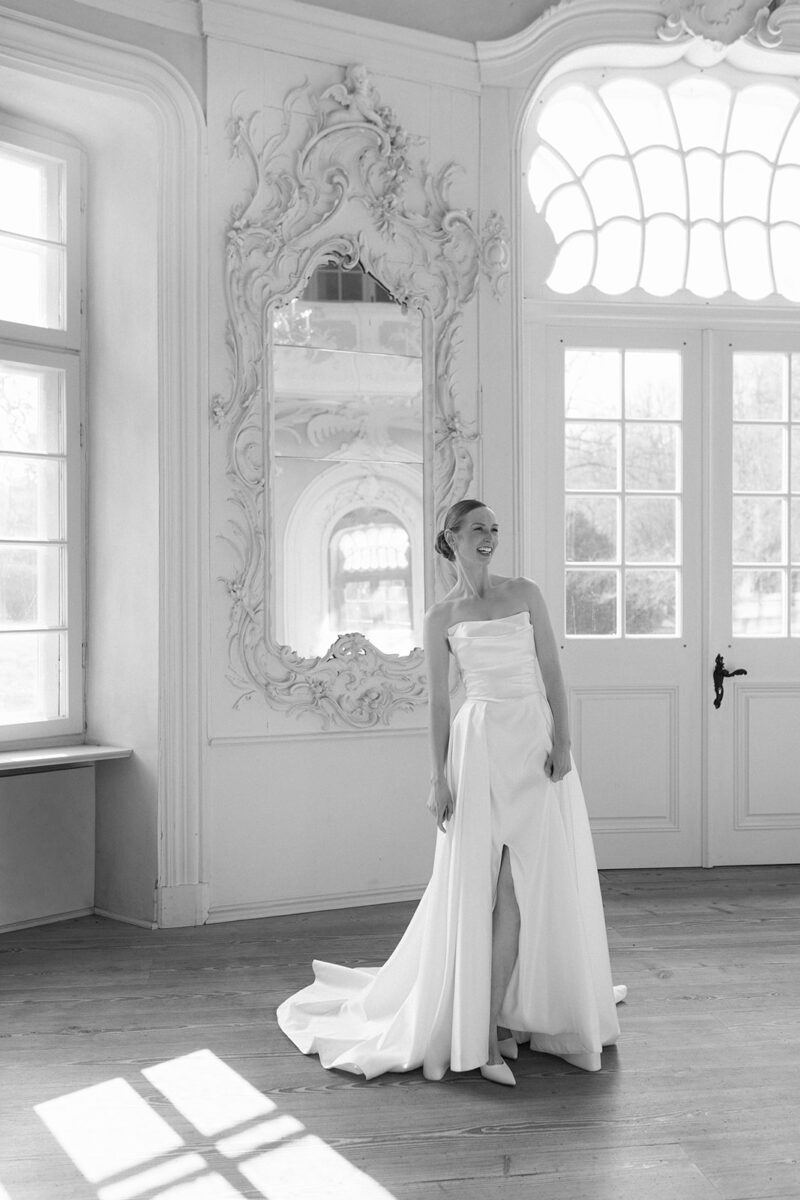 Die Braut steht im Prinzenhaus und lacht herzlich, alles wirkt locker und leicht, das Bild ist schwarzweiß.