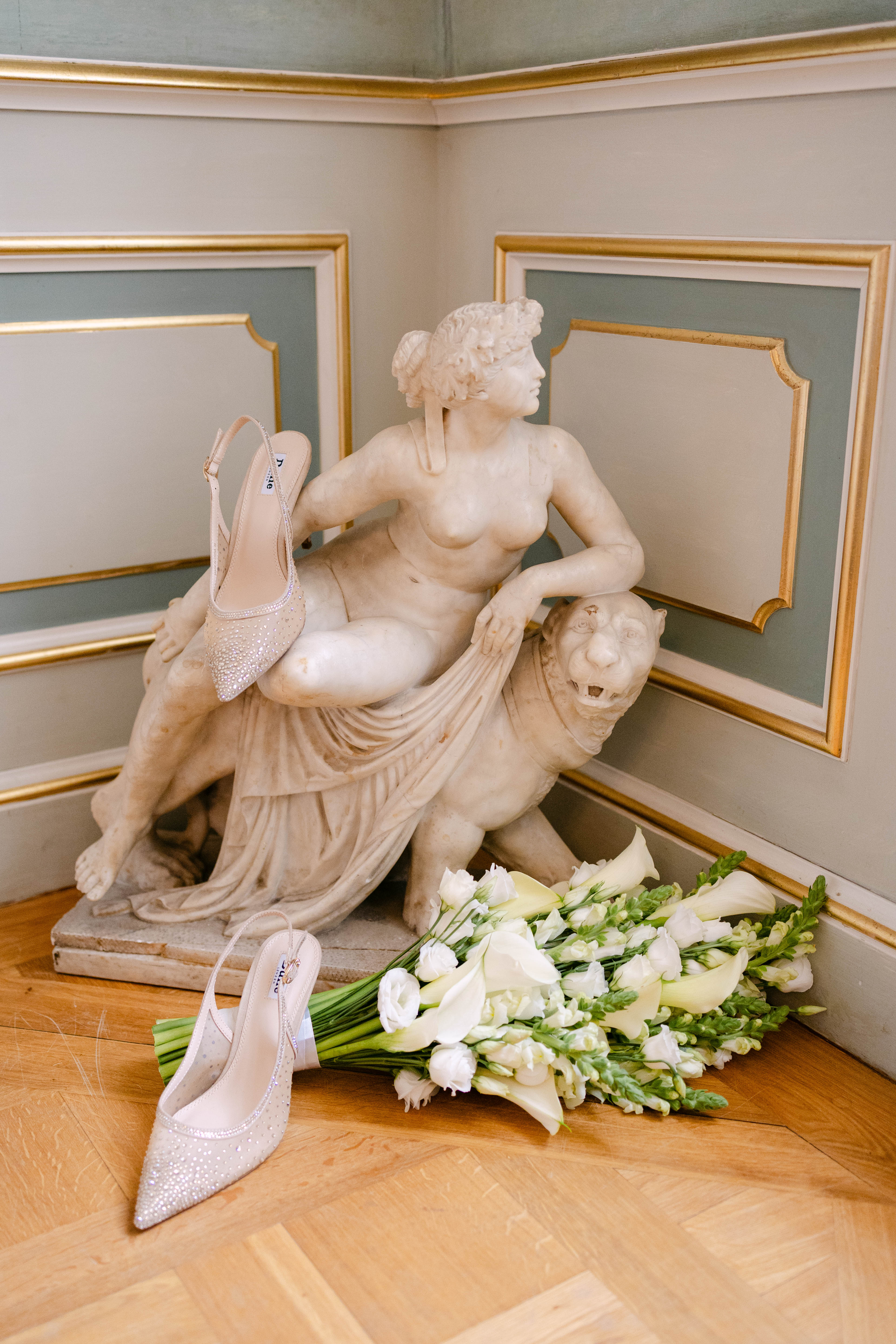 Brautstrauß und Brautschuhe liegen auf einer Statue im Schloss Friedrichsfelde